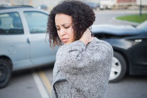Woman with Whiplash after an auto injury holds neck in pain